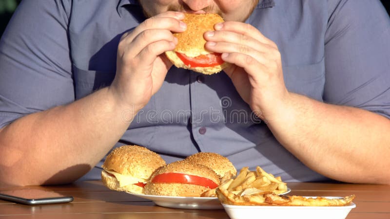 Hamburger grassi mangiatori di uomini affamati obesi, dipendenza non sana dell'alimento, sovrappeso