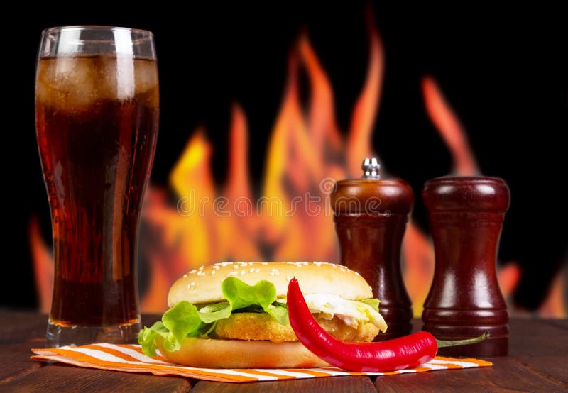 Hamburger, kola, Spaanse pepers en kruiden op achtergrond van vlammen royalty-vrije stock afbeelding Hamburger, kola, Spaanse pepers en kruiden op achtergrond van vlammen royalty-vrije stock afbeelding