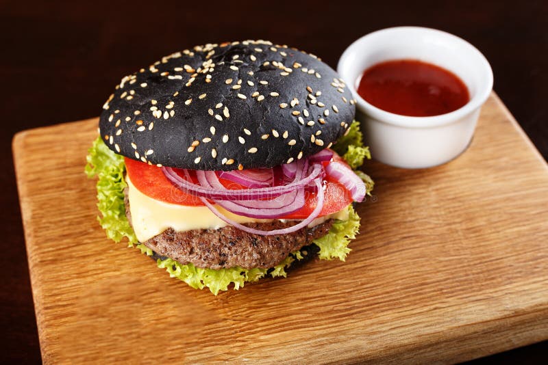 Hamburger nero sul bordo fotografia stock Hamburger nero sul bordo fotografia stock