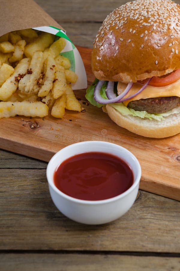 Hamburger, patate fritte e salsa al pomodoro sulla tavola immagine stock libera da diritti Hamburger, patate fritte e salsa al pomodoro sulla tavola immagine stock libera da diritti
