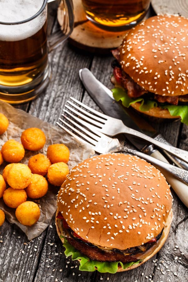 Hamburguer delicioso com as bolas e cerveja fritadas da batata foto de stock royalty free Hamburguer delicioso com as bolas e cerveja fritadas da batata foto de stock royalty free