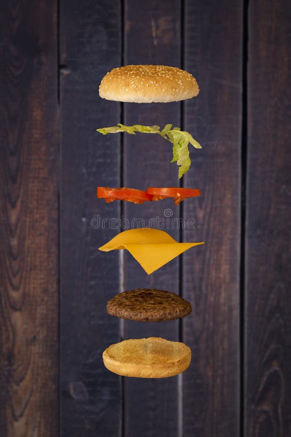 Hamburguesa que flota con el fondo de madera fotografía de archivo Hamburguesa que flota con el fondo de madera fotografía de archivo