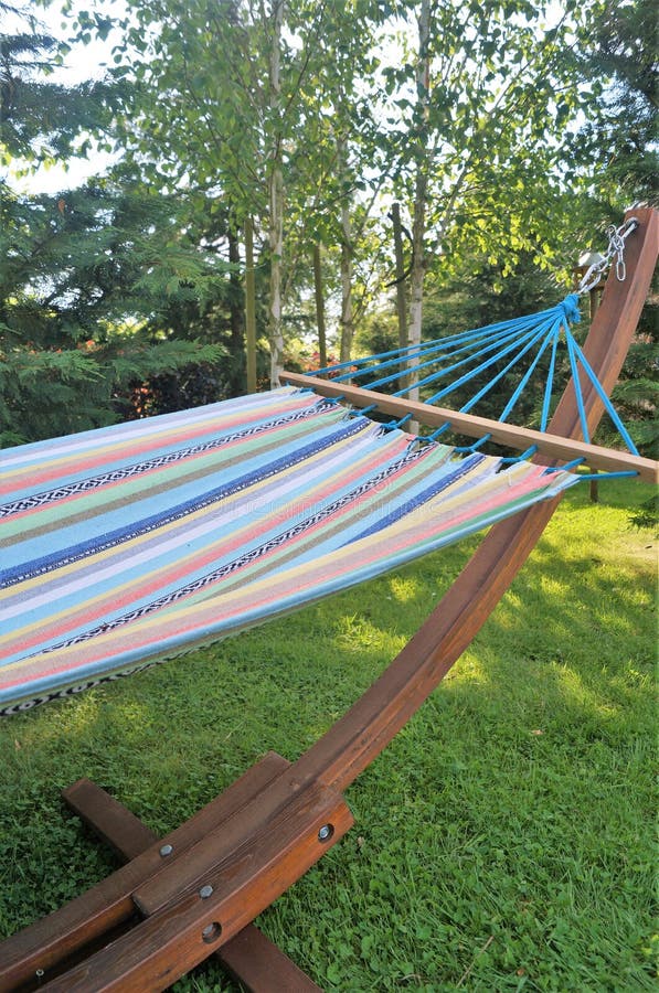 A colorful garden hammock rests in the shade on a summer evening. A colorful garden hammock rests in the shade on a summer evening