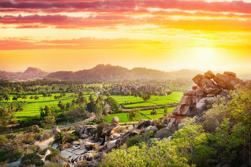 Blick auf Reis-Plantage von oben Affen Hanuman-Tempel auf einem Hügel bei Sonnenuntergang in Hampi, Karnataka, Indien.