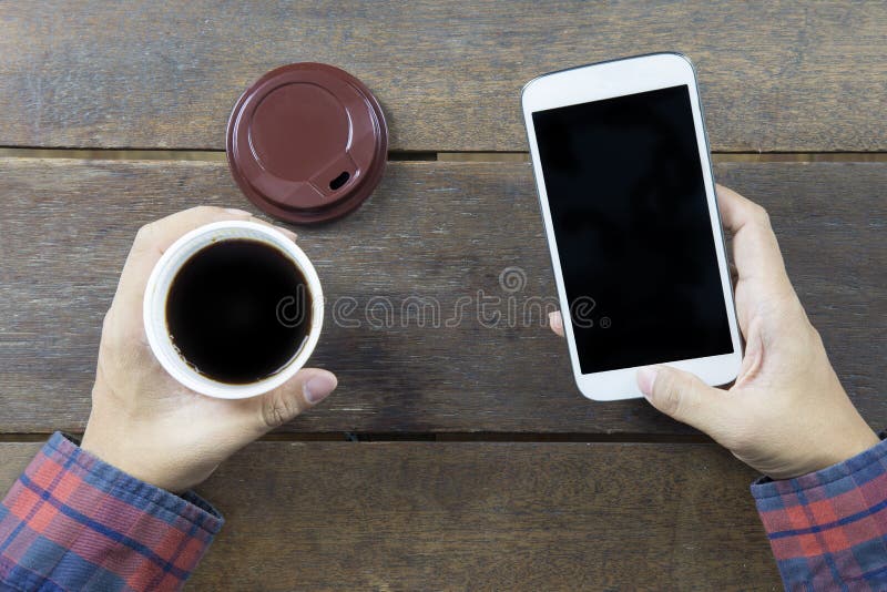 Hand of Asian man in long shirt holding black coffee.