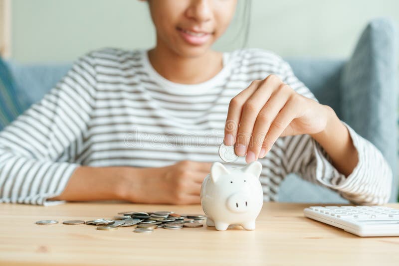Hand of Asian young girl are putting coins in a piggy bank at home, Close up of child happy smile, retirement, finance and. Saving money for future concept stock photos Hand of Asian young girl are putting coins in a piggy bank at home, Close up of child happy smile, retirement, finance and. Saving money for future concept stock photos