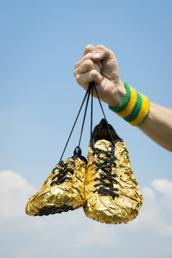 Hand of Athlete Holding Gold Running Shoes royalty free stock images Hand of Athlete Holding Gold Running Shoes royalty free stock images