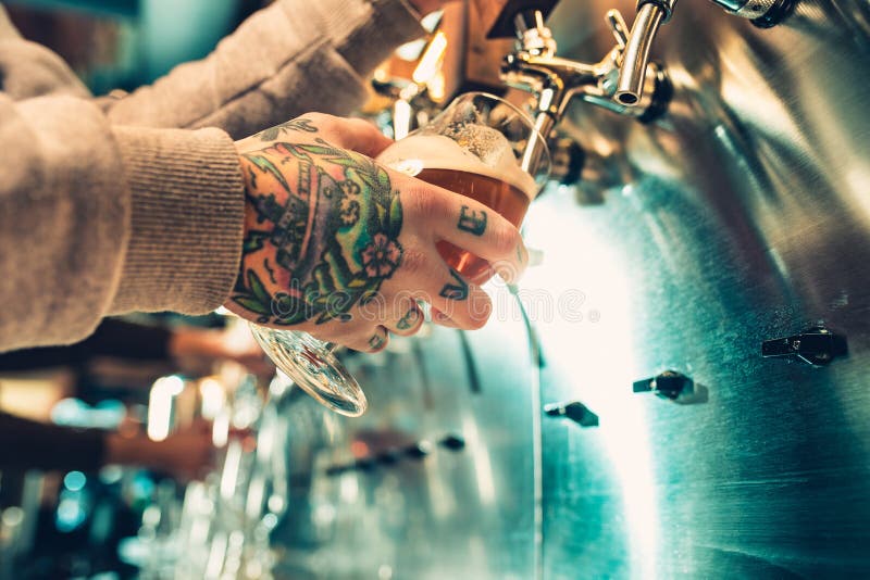 Hand av bartendern som häller ett stort lageröl i klapp arkivbilder Hand av bartendern som häller ett stort lageröl i klapp arkivbilder