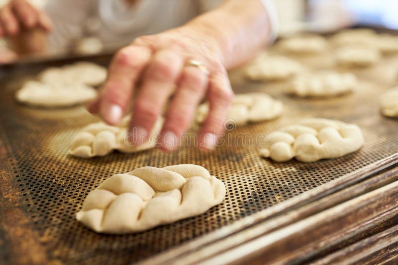 Hand of a Baker Baking Yeast Plaited Bread on a Tray Stock Image