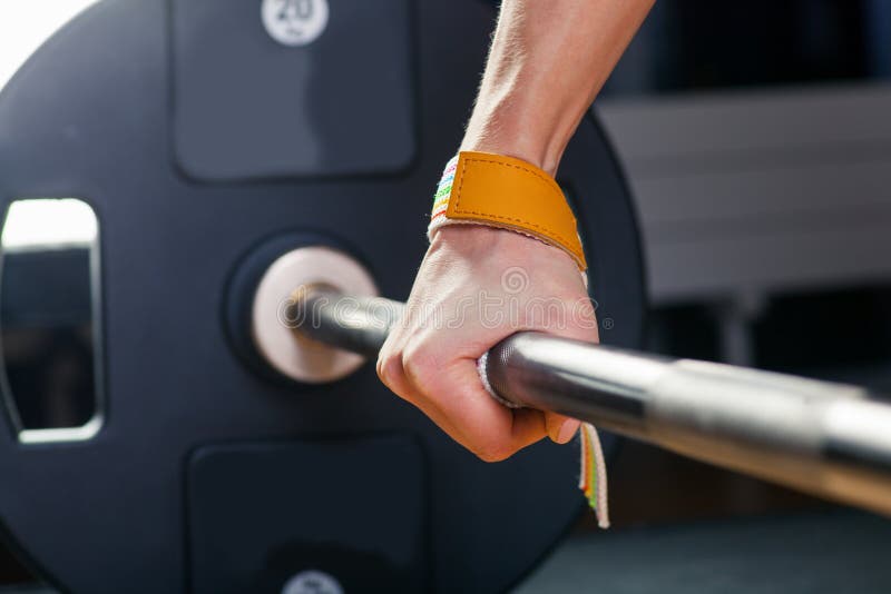 Hand on the barbell. Young athlete getting ready for weight lifting training. carpal bandage