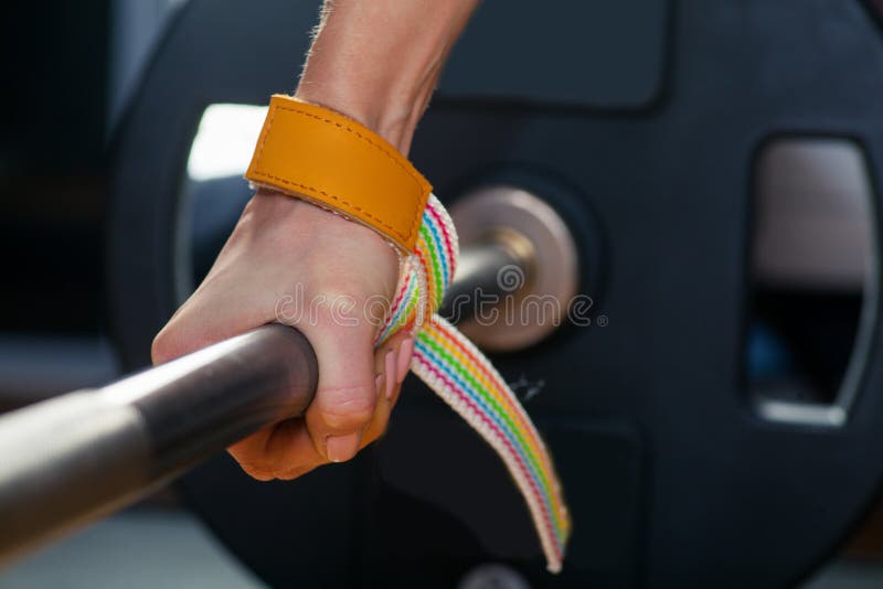 Hand on the barbell. Young athlete getting ready for weight lifting training. carpal bandage