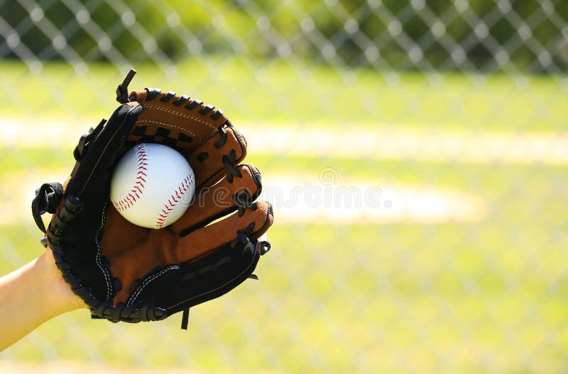 Hand of Baseball Player with Glove and Ball over Field and Net