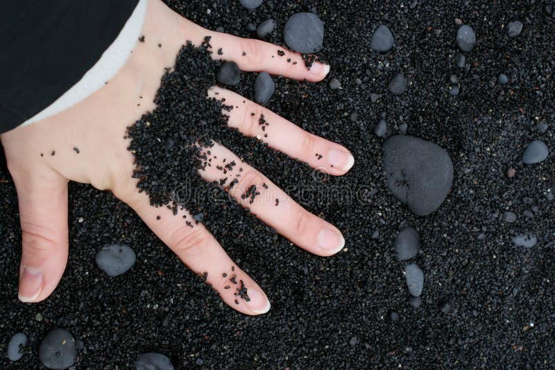 Hand in black sand