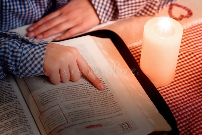 Hand on book beside candle.