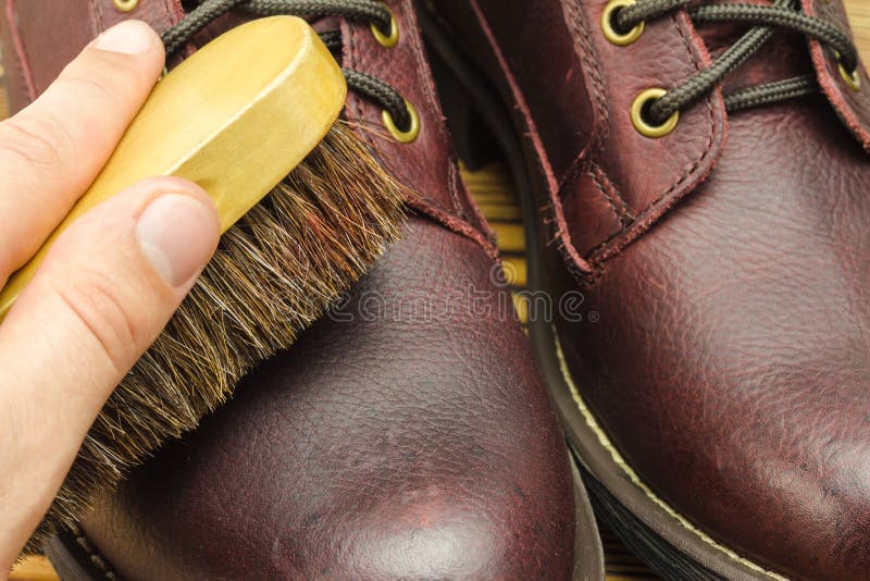 Hand with Brush, Care Clean and Polishing Brown Leather Boots, Close-up View. Stock Photo