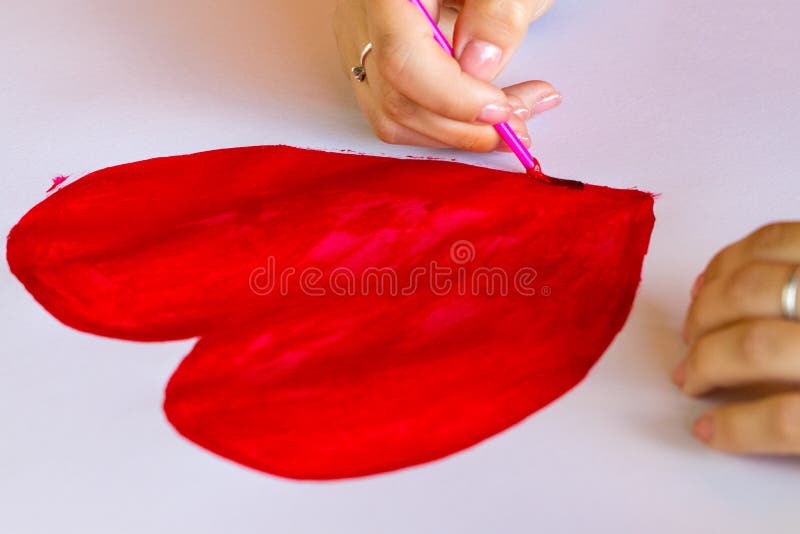 Hand with Brush Drawing Shape of Heart Isolated on White Stock Image