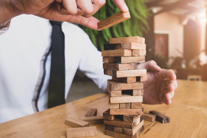 Hand of business man is planning about rick for business with wooden blocks