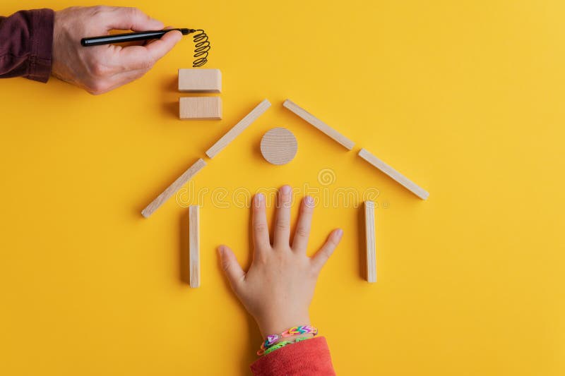 Hand of a child in a house build of wooden pegs and blocks