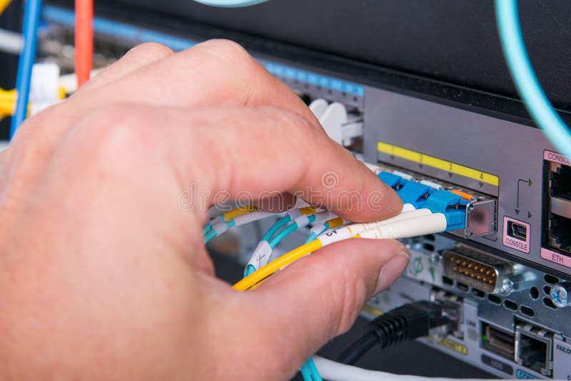 Hand of Computer Engineer Connecting Fiber Optic Cable in Server Stock