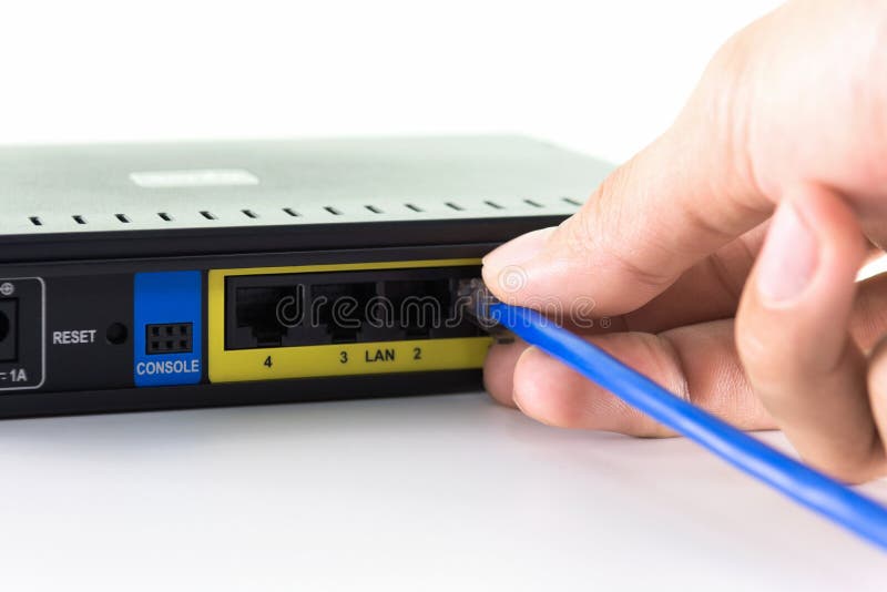 Hand connecting a yellow network cable on a network port of a router