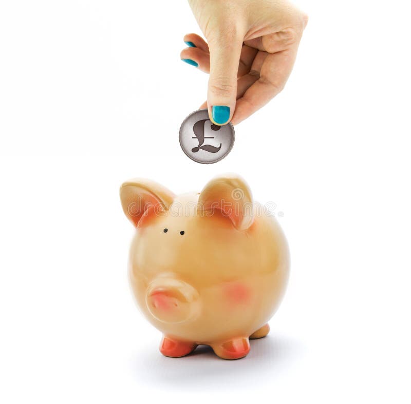 Hand depositing coin with British pound sign in piggy bank isolated on white