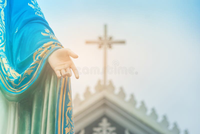 Hand der gesegneten Jungfrau- Mariastatue, die vor Roman Catholic Diocese mit Kruzifix oder Kreuz steht