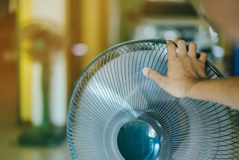 Hand der Note des jungen Mannes und auf vorderen Grills des elektrischen Ventilators auf einen guten Wind in seinem Haus im Somme stockfotos Hand der Note des jungen Mannes und auf vorderen Grills des elektrischen Ventilators auf einen guten Wind in seinem Haus im Somme stockfotos