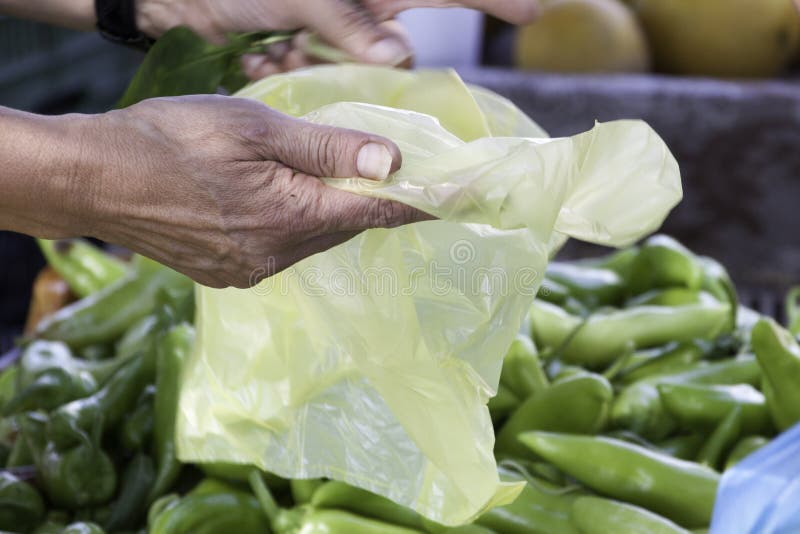 Hand die een gele plastic zak houden bij kruidenierswinkel stock afbeelding Hand die een gele plastic zak houden bij kruidenierswinkel stock afbeelding