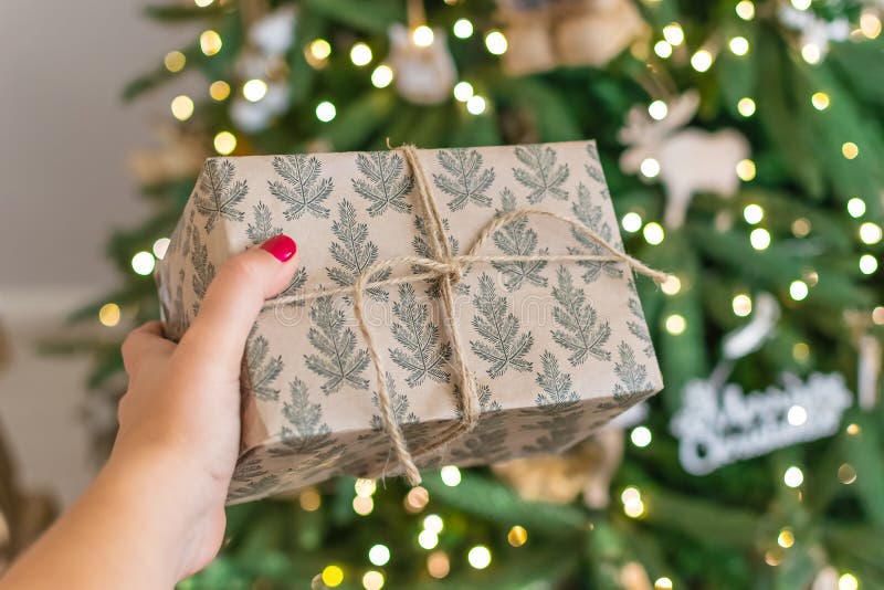 Hand die een gift standhouden aan de Kerstboom Het Nieuwjaar is 2019 zolderboom in rustieke die stijl, gift met een kabel wordt g royalty-vrije stock afbeelding Hand die een gift standhouden aan de Kerstboom Het Nieuwjaar is 2019 zolderboom in rustieke die stijl, gift met een kabel wordt g royalty-vrije stock afbeelding