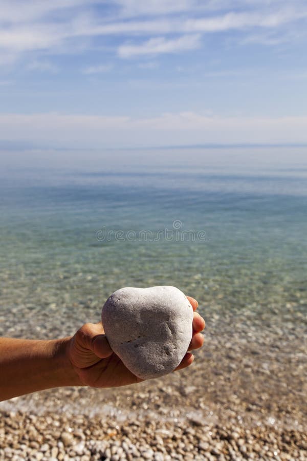 Hand die een natuurlijke hart-vormige steen houden stock fotografie Hand die een natuurlijke hart-vormige steen houden stock fotografie