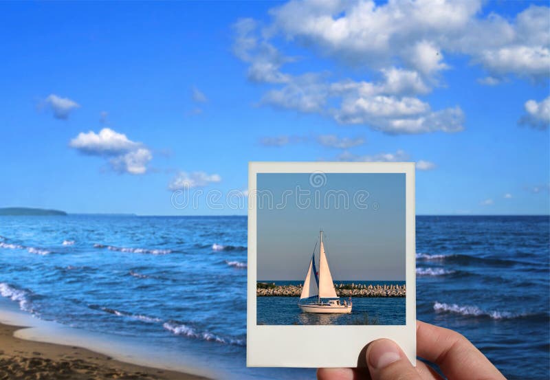 Hand holding a holiday photo, beautiful seashore in background, photo inside is my property. Hand holding a holiday photo, beautiful seashore in background, photo inside is my property