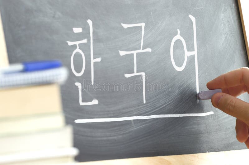 Hand die op een bord in een Koreaanse klasse met het woord & x22 schrijft; Korean& x22; schreef binnen