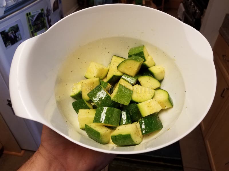 Hand die witte kom van stukken van courgette houden royalty-vrije stock afbeeldingen Hand die witte kom van stukken van courgette houden royalty-vrije stock afbeeldingen