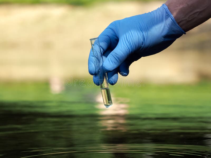 Water sample. Hand in glove holding a test tube of clear water. Concept - water purity analysis, environment, ecology. Water testing for infections, permission to swim. Water sample. Hand in glove holding a test tube of clear water. Concept - water purity analysis, environment, ecology. Water testing for infections, permission to swim