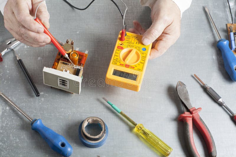 Hand of electrician with multimeter probe at electrical switchgear cabinet. Engineering tools stock image Hand of electrician with multimeter probe at electrical switchgear cabinet. Engineering tools stock image