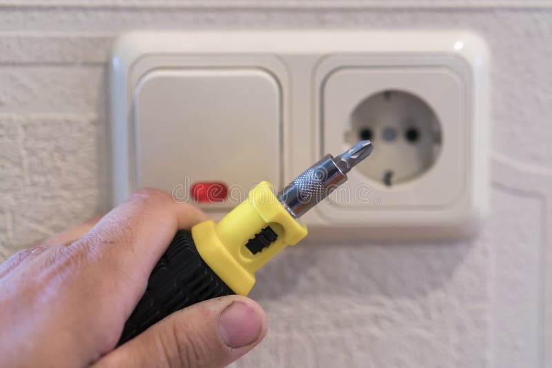 Hand Of An Electrician To Repair A Wall Socket. Closeup of man electrician's hand repairing an electrical outlet. Hazardous royalty free stock photo Hand Of An Electrician To Repair A Wall Socket. Closeup of man electrician's hand repairing an electrical outlet. Hazardous royalty free stock photo
