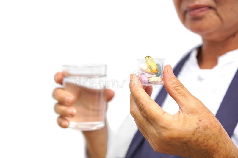 Female elderly holding a cup of multi vitamin tablets