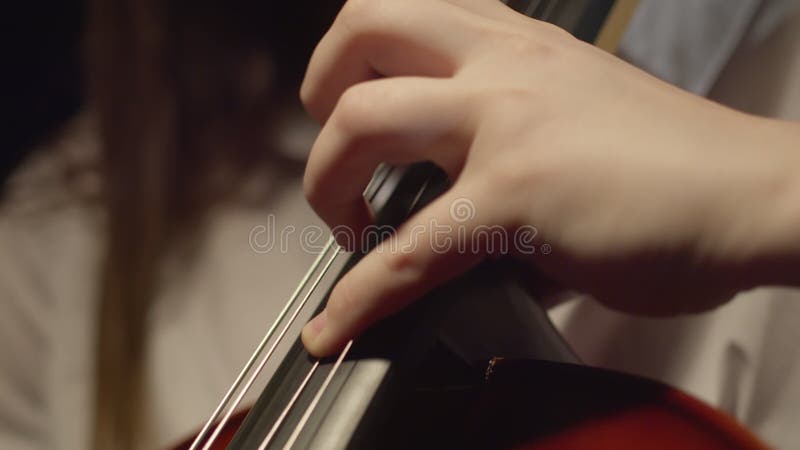 Hand of female musician playing with bow and fingers on strings of cello at concert, closeup. Female musician plays stock video footage