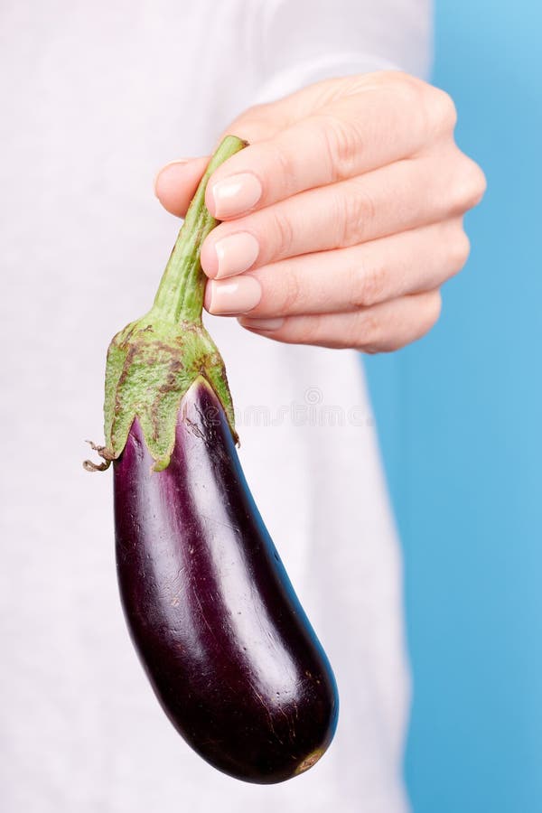 Hand with Fresh Ripe Purple Eggplant on Blue Background Stock Photo