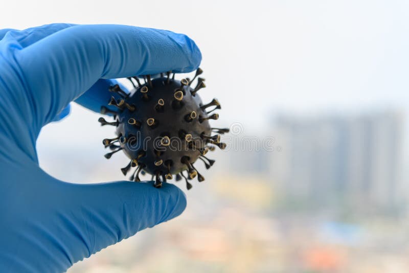 Hand with glove catching a coronavirus model in front of buildings royalty free stock images Hand with glove catching a coronavirus model in front of buildings royalty free stock images