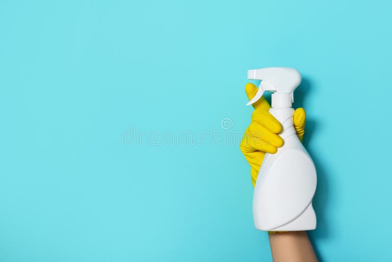 Hand in glove holding white plastic bottle of cleaning product, household chemicals. Copy space. Cleaning service concept.