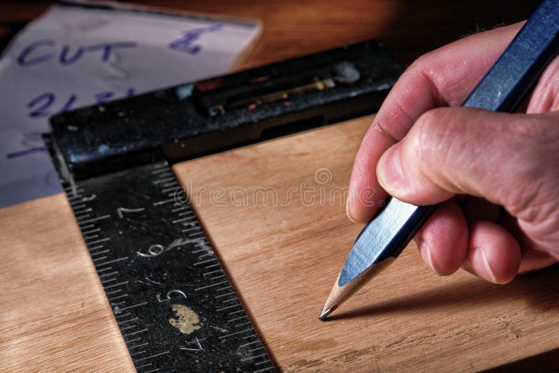 Timmermanspotlood en winkelhaak in de hand van een houtbewerker stock afbeelding