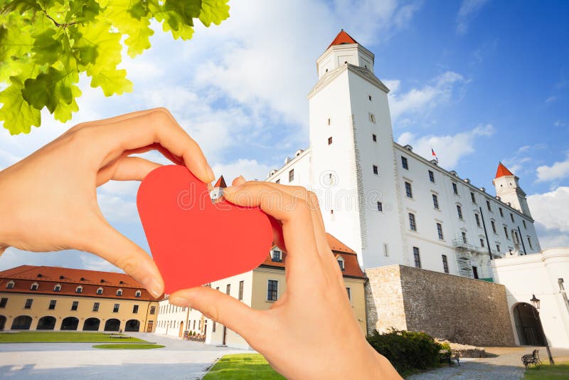 Hand hold red heart over Castle yard in Bratislava