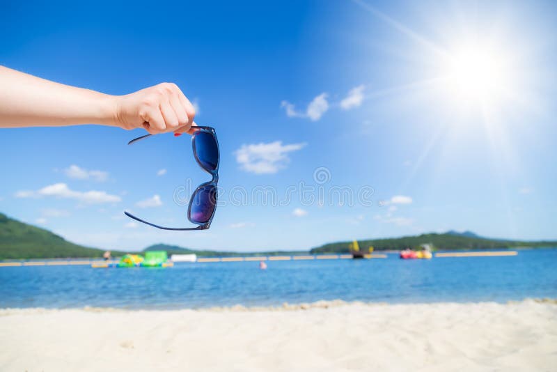 Hand hold sunglasses with sandy beach royalty free stock photo Hand hold sunglasses with sandy beach royalty free stock photo