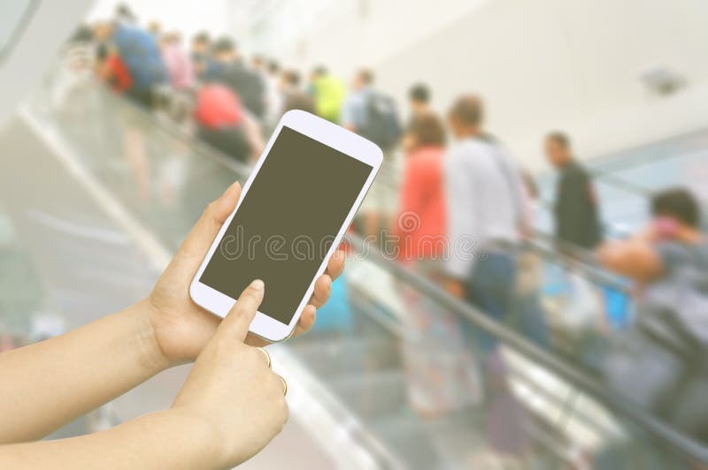 Hand hold and touch screen with people are going up the escalator in the Airport. Blur stock photography Hand hold and touch screen with people are going up the escalator in the Airport. Blur stock photography