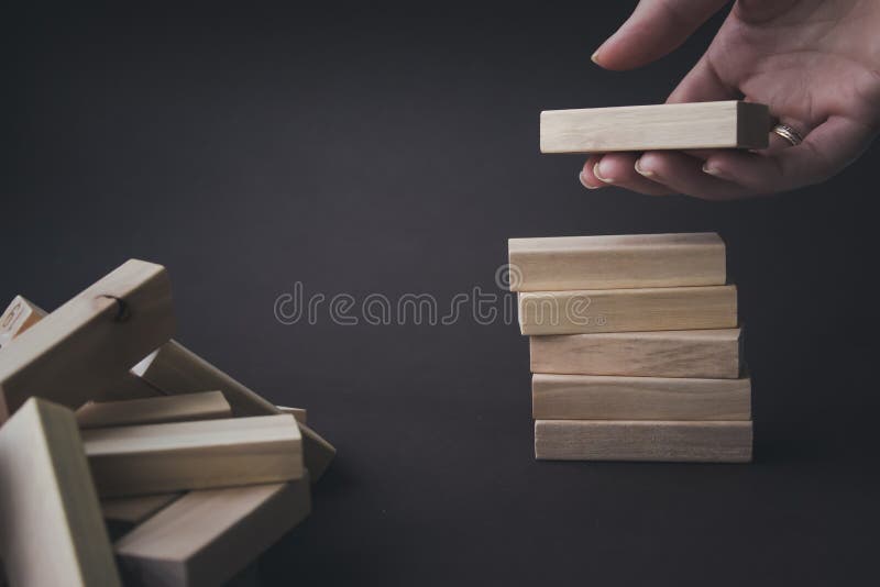 Hand hold a wooden block under stack of the same blocks. Leader, individuality, best worker, best employee, idea, team. Business conceptual image.