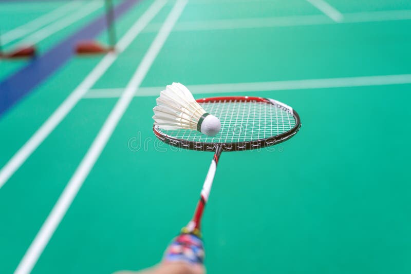 Hand Holding Badminton Shuttlecock with Racket on Court Stock Photo