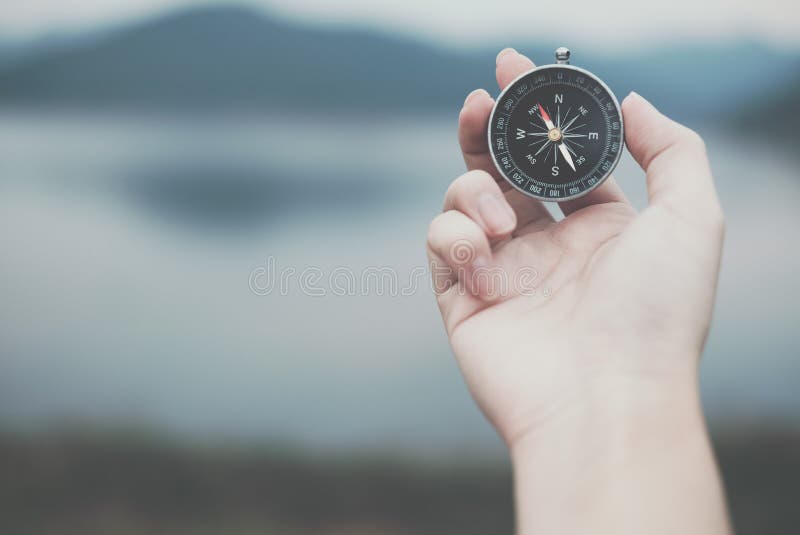 hand holding compass for searching direction outdoor. man seeking way with nature background. travel lifestyle, summer vacation c