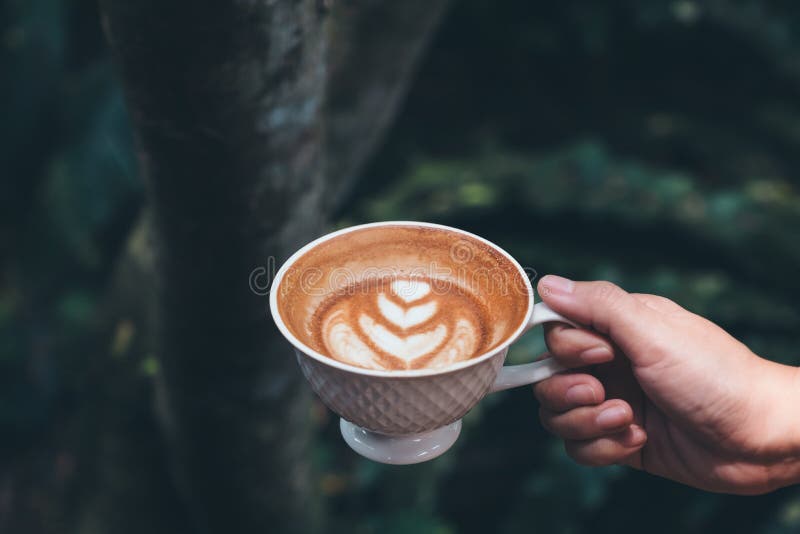 Download A Hand Holding Cup Of Hot Latte Coffee With Heart Art In Green Download A Hand Holding Cup Of Hot Latte Coffee With Heart Art In Green