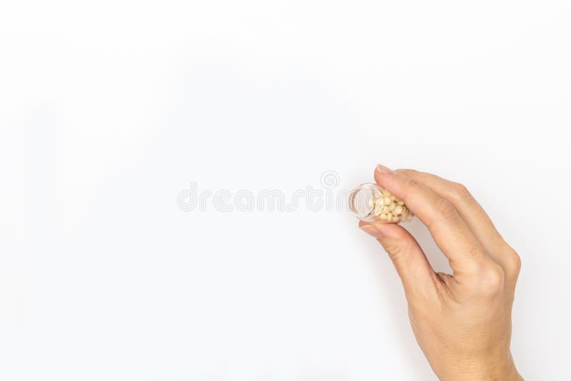 Hand holding a glass bottle with pills, patient taking pills and following doctor prescription, white background copy space